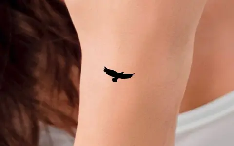 Mały tatuaż orzeł w locie na skórze. Symbol wolności i siły.