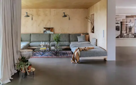 Sofá modular gris, alfombra oriental, mesa de centro de cristal y detalles de interiorismo años 60.