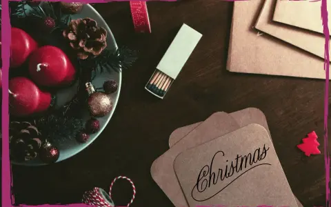 Candele rosse, pigne e decorazioni natalizie su un tavolo scuro, pronte per scrivere una poesia di Natale per adulti.