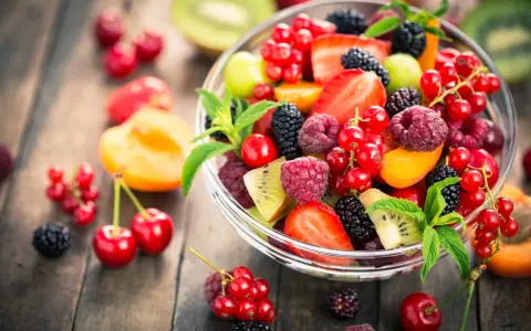 Ciotola di frutta fresca con fragole, lamponi, ribes, more e kiwi, un'ottima scelta di frutta con meno zuccheri.