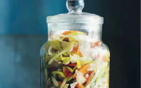 En glasburk fylld med strimlad vitkål, morötter och purjolök, redo för en 3 veckors sallad.
