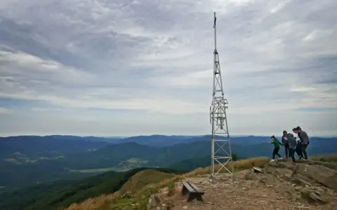 Grupa turystów podziwia widok na góry z wieżą telekomunikacyjną. Smerek z Wetliny wita wędrowców.