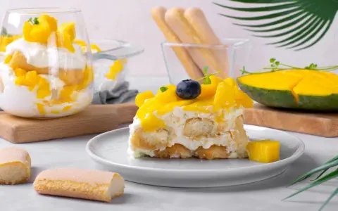 Un délicieux tiramisu mangue, garni de fruits frais et de biscuits à la cuillère. Une touche tropicale pour un dessert rafraîchissant.