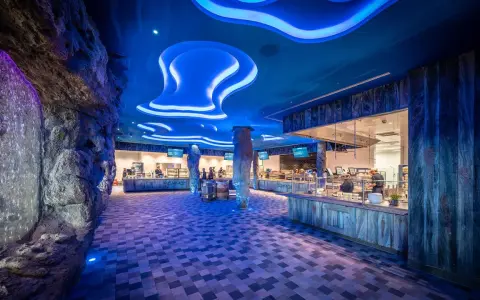 Einzigartiges Ambiente im Rulantica Essen: Wasserfall, Felsen und blaue Wellen beleuchten die Essensausgabe.