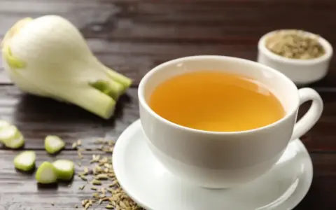 Una taza de infusión de hinojo por la noche, con hinojo fresco y semillas esparcidas.