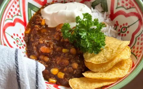 En skål med chili con carne, ris, gräddfil och tortillachips. Perfekt vin till chili con carne!