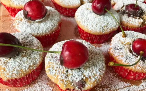 Saftige kirsch muffins, bestäubt mit Puderzucker und garniert mit frischen Kirschen. Ein süßer Genuss!