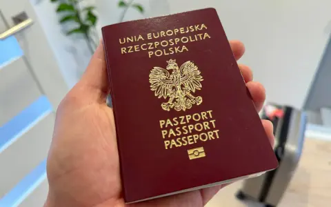 Polski paszport w dłoni. Czy do USA potrzebna jest wiza? Podróż w toku, walizka czeka.