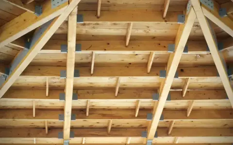 Widok od dołu na konstrukcję dachu z widocznymi belkami i krokwi. To strop drewniany, a nie betonowy.