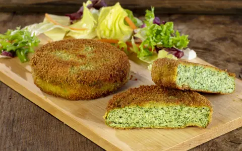 Deliziose spinacine fatte in casa, dorate e croccanti, servite con un'insalata fresca su un tagliere di legno.
