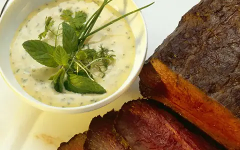 Sauce crémeuse aux herbes pour accompagner un rôti de bœuf juteux, garnie de menthe fraîche et de ciboulette.