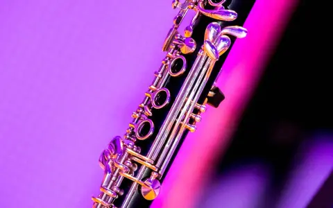 Zbliżenie na klarnet, piękny instrument dęty drewniany, z błyszczącymi klapami na tle fioletowo-różowego światła.
