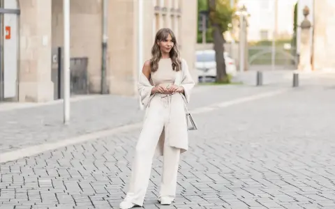 Eine Frau in einem cremefarbenen Outfit mit weiten Leinenhosen, das perfekt für den Sommer ist. So kann man Leinenhose kombinieren Damen!