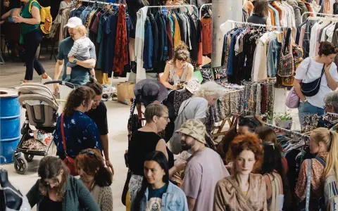 Menschen stöbern auf einem belebten **bazar de nuit** nach Kleidung und Accessoires.