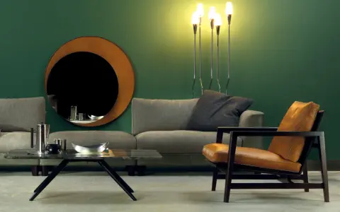 Elegante soggiorno con divano grigio, poltrona in pelle color cuoio e specchio rotondo. Idee su come abbinare divano e poltrone diverse.
