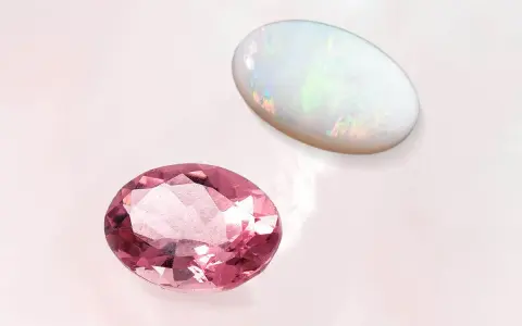 Two oval gemstones, a pink tourmaline and a white opal, are displayed. The opal's play-of-color makes it a perfect october 27 birthstone.