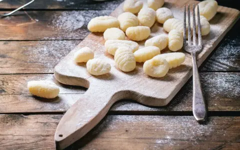 Gnocchi fatti in casa su tagliere di legno, spolverati di farina. L'impasto gnocchi troppo appiccicoso ha reso la preparazione un po' complicata, ma il risultato è invitante.