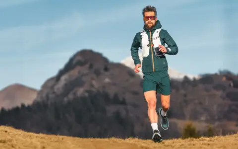 Ein Mann läuft in den Bergen, was ist ein ultramarathon? Er trägt Laufkleidung und eine Weste.