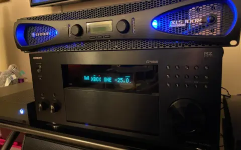 Wzmacniacz Crown XLS 1002 z niebieskim podświetleniem, umieszczony nad amplitunerem Onkyo.