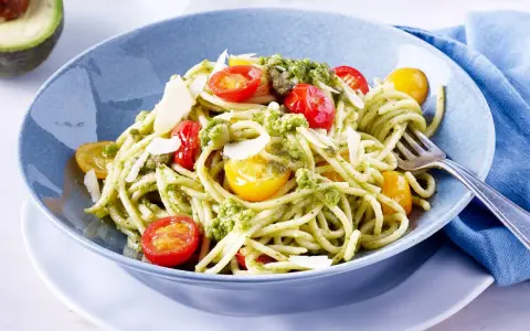 Spaghetti mit cremigem Avocado Pesto, Kirschtomaten und Parmesan.