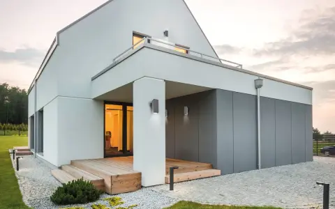 Nowoczesne oświetlenie elewacji podkreśla architekturę domu. Lampy ścienne i stojące tworzą przytulną atmosferę.