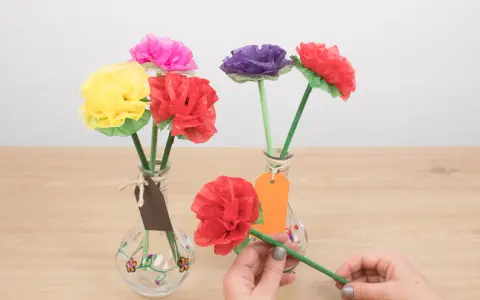 Flores de colores hechas con manualidades de papel de seda, en jarrones decorados.