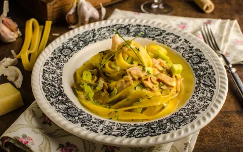 Makaron tagliatelle w kremowym sosie curry z kurczakiem i porem, ozdobiony szczypiorkiem.