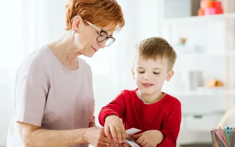 Babcia pomaga wnuczkowi w zajęciach, które mogą być częścią terapii stereotypii ruchowych.