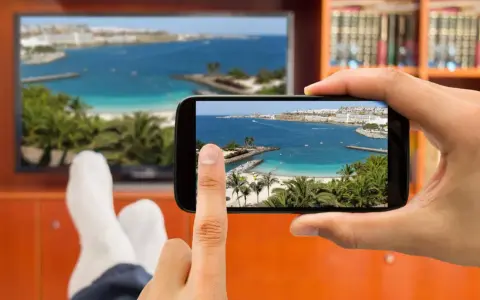 Jak podłączyć telefon do telewizora przez HDMI? Widok na plażę z palemami na ekranie telefonu i telewizora.