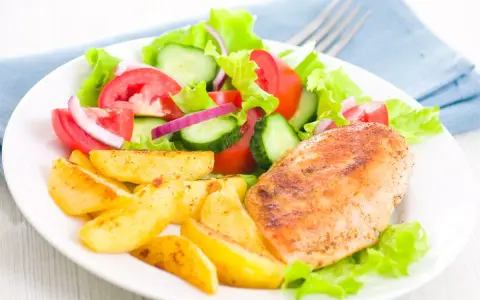 Petto di pollo in friggitrice ad aria, patate arrosto e insalata fresca con pomodori, cetrioli e cipolla rossa.