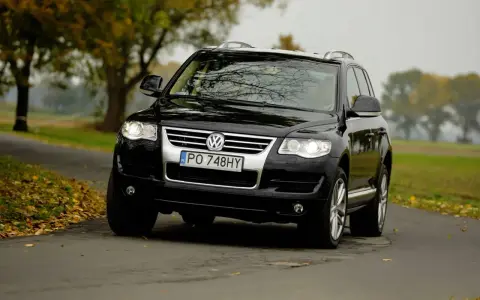 Czarny VW Touareg 2.5 TDI R5 na jesiennej drodze. Choć to solidne auto, warto znać jego potencjalne wady.