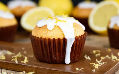 Zitronenmuffins mit weißer Glasur und Zitronenschale, die an eine Backmischung für Zitronenmuffins erinnern.