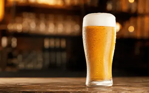 Schłodzony pilsner z obfitą pianką na blacie drewnianego baru.