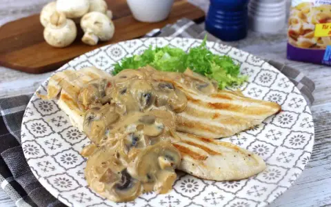 Sabroso pollo con champiñones en salsa cremosa, servido con lechuga fresca en un plato decorado.