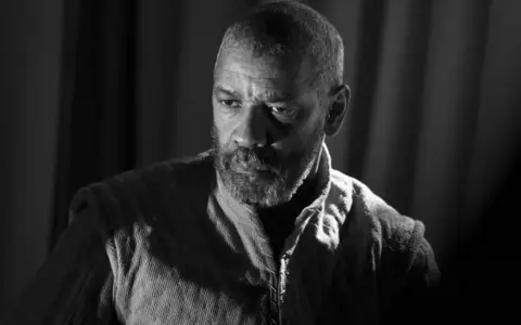 Denzel Washington jako Makbet w mrocznej epoce. Jego spojrzenie zdradza wewnętrzne rozterki i ambicje.