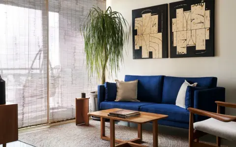 Salones muy pequeños con encanto: sofá azul vibrante, mesa de centro de madera, planta frondosa y arte abstracto en las paredes.