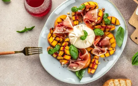 Gegrillte Pfirsiche mit cremigem Burrata, Prosciutto und Basilikum – ein köstlicher Pfirsich Burrata Genuss.