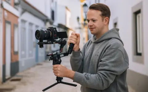Mężczyzna trzyma profesjonalny aparat do nagrywania na stabilizatorze, gotowy do uchwycenia dynamicznych ujęć na ulicy.