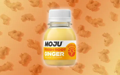 Botella de MOJU con shots de jengibre fresco, rodeada de raíces de jengibre. Un impulso de vitalidad.