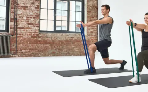 Mann und Frau machen Ausfallschritte mit Widerstandsbändern. Effektives HIIT Training für zu Hause.