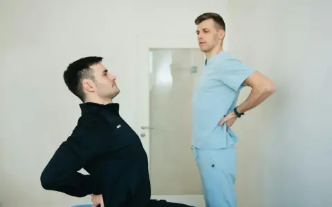 Fizjoterapeuta pomaga pacjentowi z chorobą Scheuermana w ćwiczeniach poprawiających postawę.