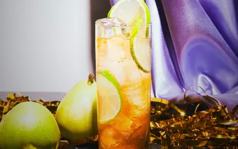 En uppfriskande drink med päron och lime, perfekt för svenska drinkar. Guldfärgad konfetti och lila tyg skapar festlig stämning.