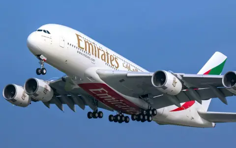 Airbus A380 Emirates z wieloma miejscami na pokładzie, wznoszący się na błękitne niebo.