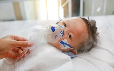 Dziecko z maską tlenową, być może z powodu RSV. Co to jest RSV? To wirus, który może być groźny dla najmłodszych.
