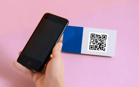 En hand håller en iPhone 6 för att scanna en QR-kod på ett kort med blått och vitt.