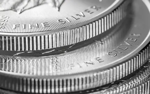 Zbliżenie na stos monet z napisem "FINE SILVER". Błyszczące srebro, idealne na prognozy inwestycyjne.