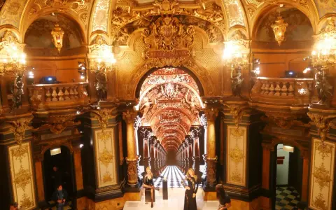 L'intérieur doré et orné du musée Grévin à Paris, avec des statues de cire et un sol à damier.