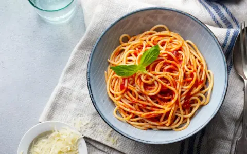 Misternie ułożone spaghetti z sosem pomidorowym i listkiem bazylii. Idealne jakie przyprawy do spaghetti? Sól, pieprz i odrobina czosnku.