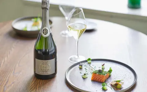Flasche Charles Heidsieck Champagner neben Lachs mit Kaviar auf einem Teller.