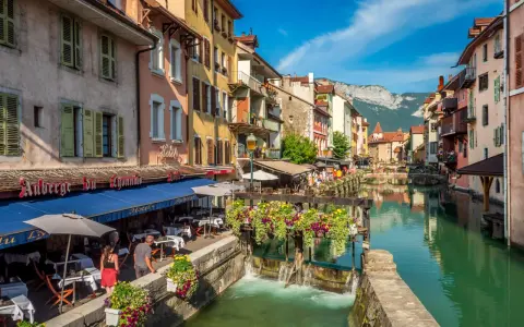 Canal animé à Annecy, avec des restaurants en terrasse et des fleurs colorées. Idéal pour découvrir les choses à faire à Annecy.